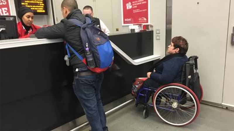 A wheelchair user at Kings Cross Station trying to use a customer service desk.