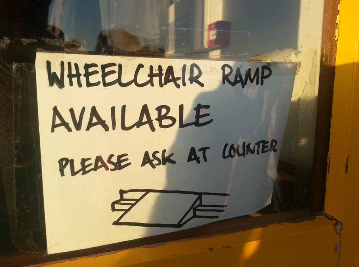 A sign in a shop window that reads: Wheelchair ramp available please ask at counter